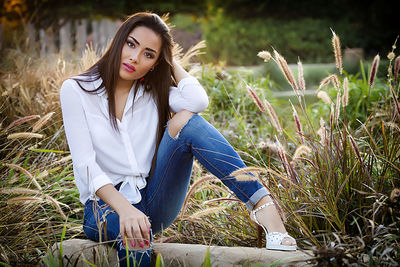 Portrait of young woman posing by plants at park