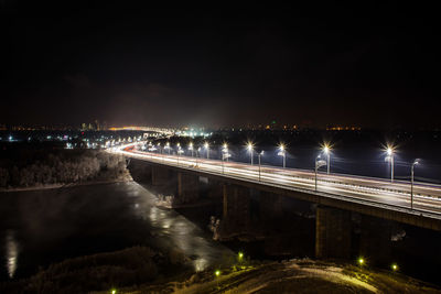 Illuminated bridge over river against sky at night