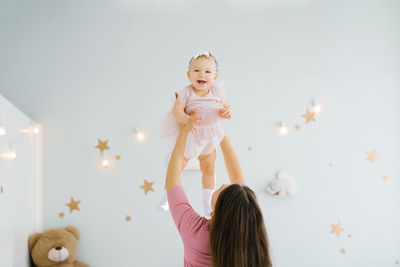 Happy family at home. the mother throws the child to her daughter and laughs.