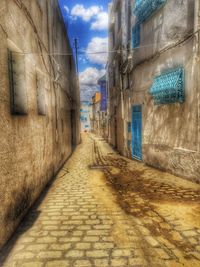 Cobblestone street amidst buildings against sky