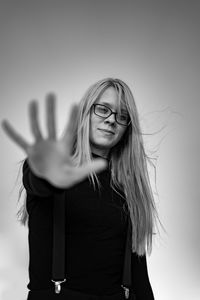 Low angle portrait of beautiful young woman gesturing while standing against clear sky