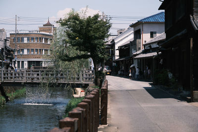 Buildings by canal against sky in city