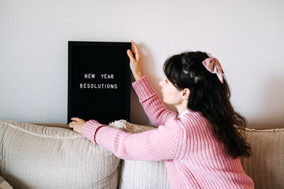 Portrait of young woman holding box against wall