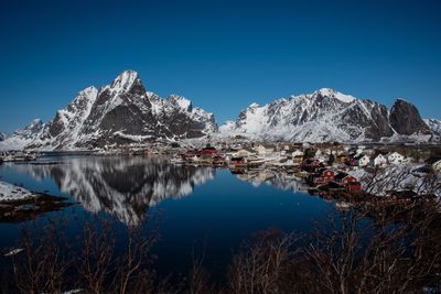 Scenic view of lake and snowcapped mountains against clear blue sky