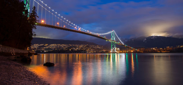 Illuminated suspension bridge over river at night