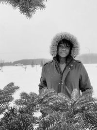 Portrait of woman standing by plants during winter