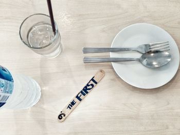 High angle view of drink by cutlery with text on stick at table