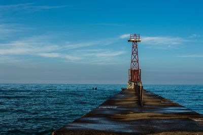 Lighthouse by sea against blue sky