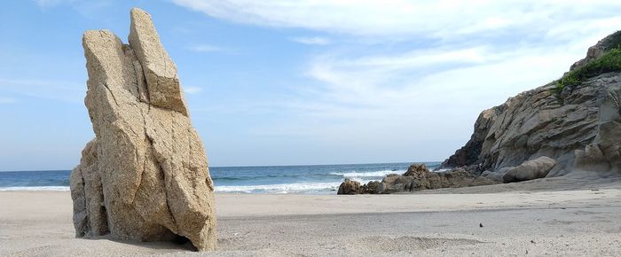 Rock formation on beach against sky