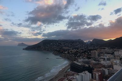 Panoramic view of sea and buildings against sky at sunset