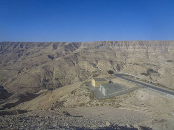 Scenic view of arid landscape against clear blue sky