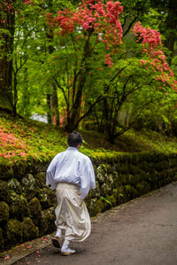 Rear view of man walking on footpath amidst trees