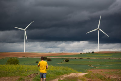 Rear view of windmill on field against sky