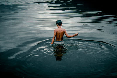 Rear view of shirtless man in lake