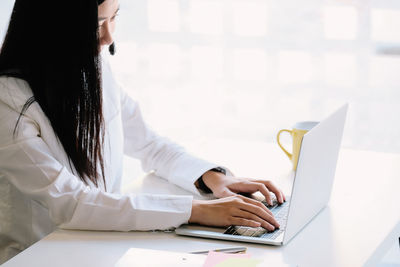 Midsection of woman using mobile phone while sitting on table