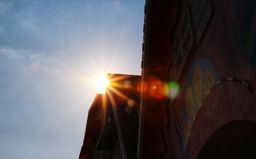 Low angle view of sunlight streaming through building during sunset