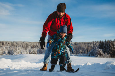 Father teaching son to cross country ski in winter wonderland norway