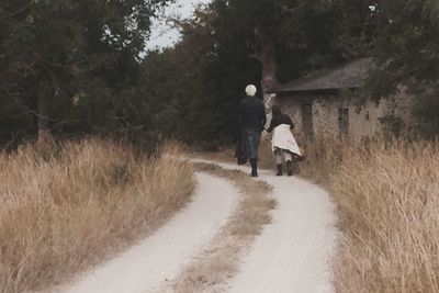 Rear view of man walking on dirt road