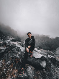 Young man standing on rock against mountains