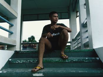 Portrait of a young man sitting on window