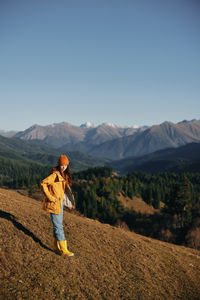 Full length of woman standing on mountain against clear sky