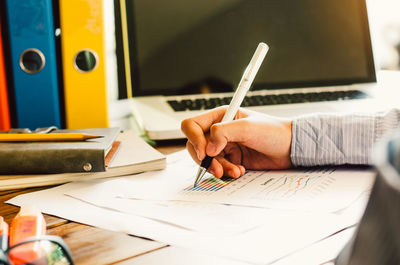 Midsection of businessman analyzing graph on office desk