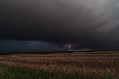 Scenic view of field against storm clouds at night