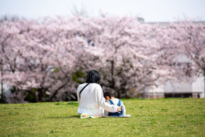 Rear view of woman sitting on grassy field
