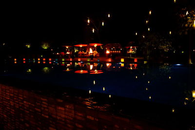 Illuminated boats against sky at night