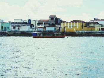 Houses by sea against sky in city