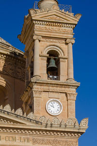 Low angle view of clock tower against blue sky