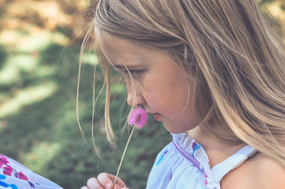 Close-up of girl holding dandelion on field