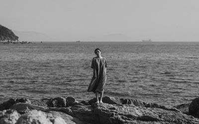 Woman standing on beach against sky