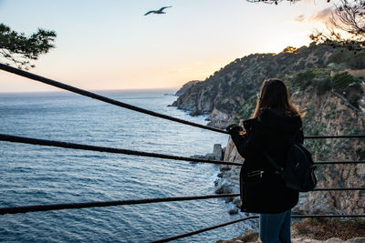 Rear view of woman looking at sea against sky