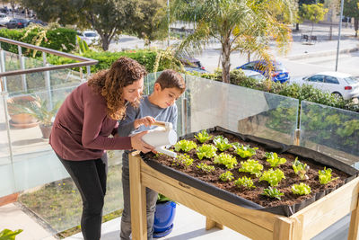 Mother and son watering vegetables in their urban garden