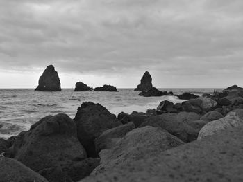 Rocks on sea shore against sky