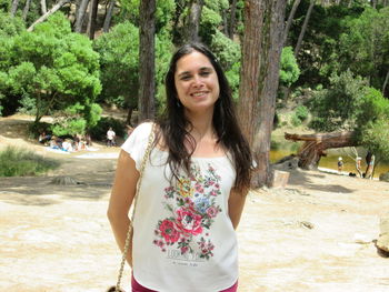 Portrait of young woman standing against trees