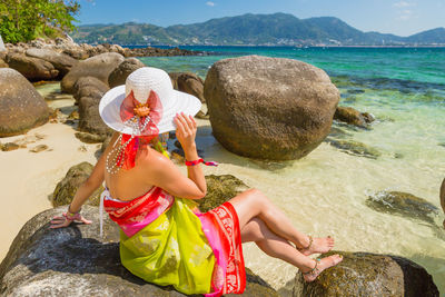 Woman sitting on rock at beach