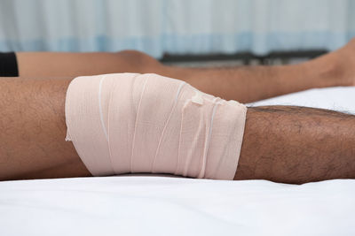 Close-up of man with bandage lying on bed