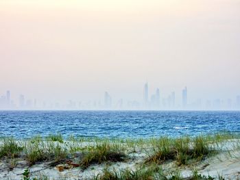 Scenic view of sea and buildings against misty sky