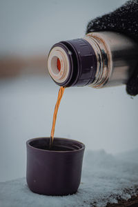 Drinking hot tea from a thermos against the view in the snowfall