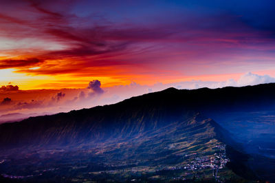 Scenic view of mountains against dramatic sky during sunset