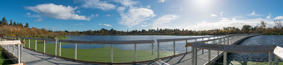 Panoramic view of swimming pool by lake against sky