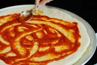 Cropped hand making pizza at home