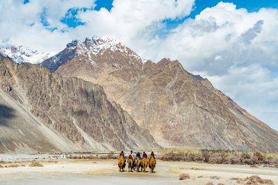 People riding motorcycle on mountain road against sky