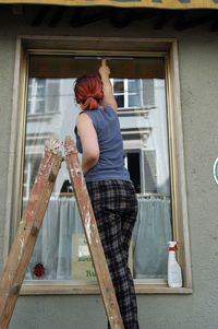 Rear view of woman standing by window