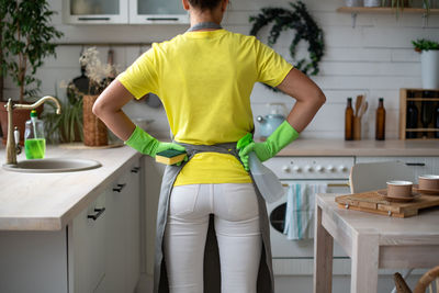 Rear view of man standing on table at home