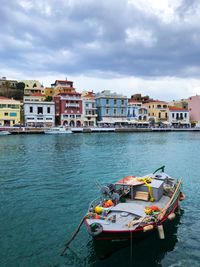 Boats moored in sea against buildings in city