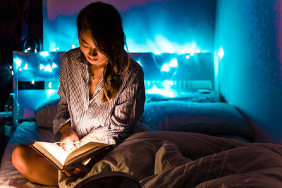 Young woman sitting on bed at home