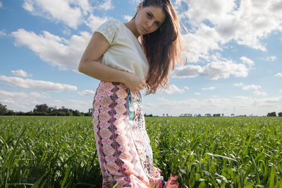 Young woman standing on field against sky